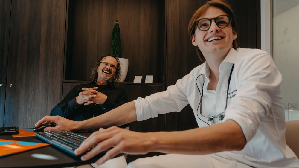 Michael im Behandlungsstuhl, eine Behandlerin erklärt am Bildschirm